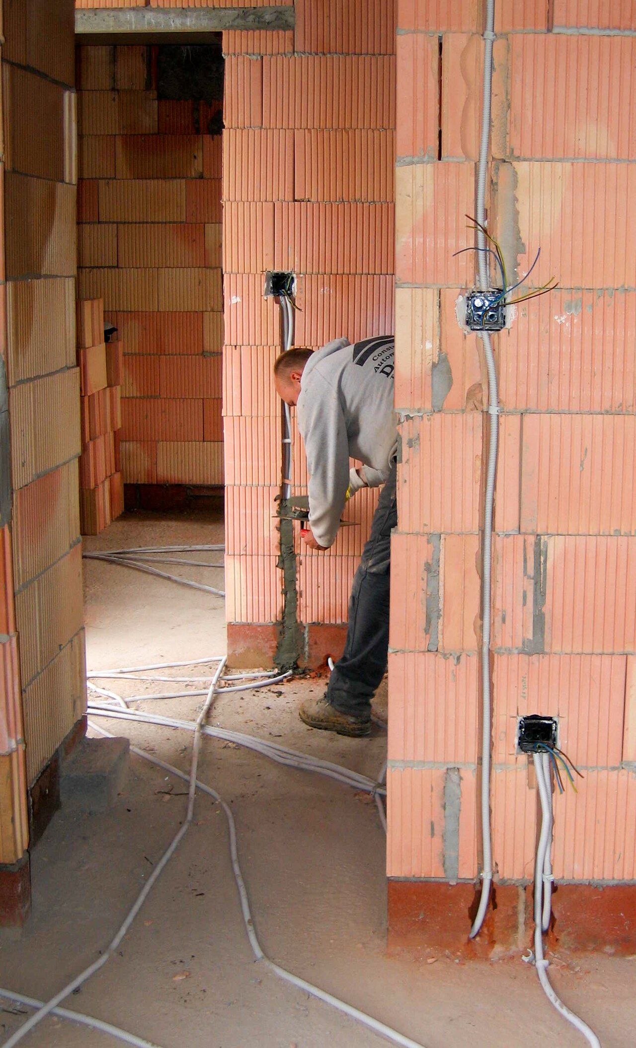 Electrician roughing in new wiring during a full house rewire before drywall closes — Bano Electrical Services Ltd